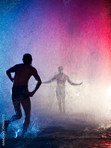 People dance beneath the downpour produced by a broken fire hydrant in Venice, Californial photo