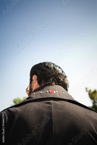 Rear view of an Elvis impersonator in a black suit.