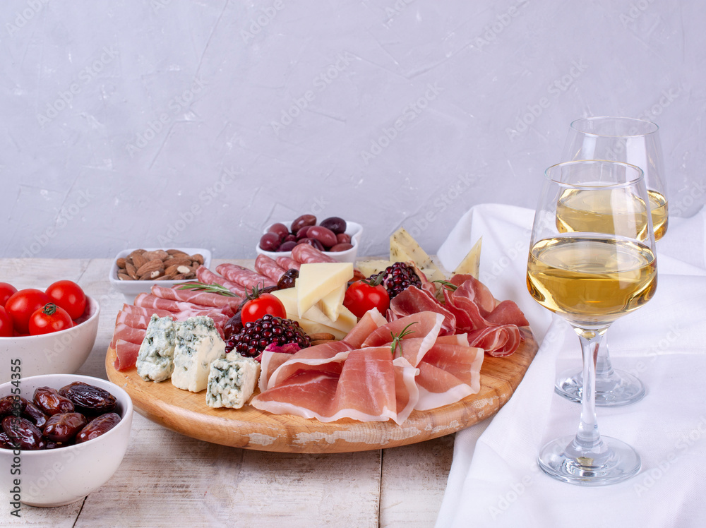 Mixed delicatessen and white wine with charcuterie and cheese board . Space for banner, logo, copy space. Italian appetizers or antipasto set with gourmet food on table Mixed delicatessen and white wine with charcuterie and cheese board . Space for banner, logo, copy space. Italian appetizers or antipasto set with gourmet food on table