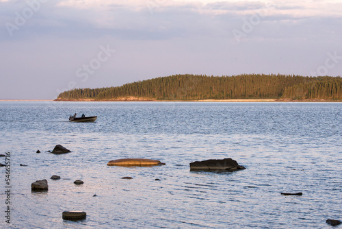 Man in boat makes his way across the waters of Lake Athabasca in Alberta, Canada. photo