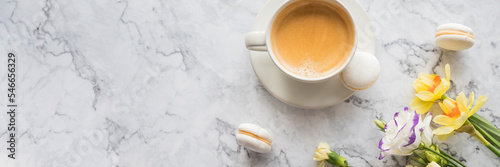 Macaroons with white cup of coffee, bright beautiful flowers on marble background.Beautiful breakfast for woman. Spring concept.Copy spaceю web banner