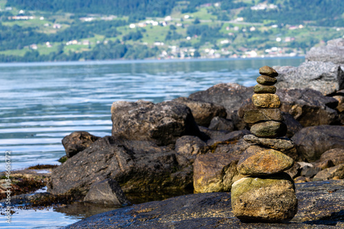 light brown and gray stones stacked on top of each other with the blue water of the fjord and the rocky coast in the background