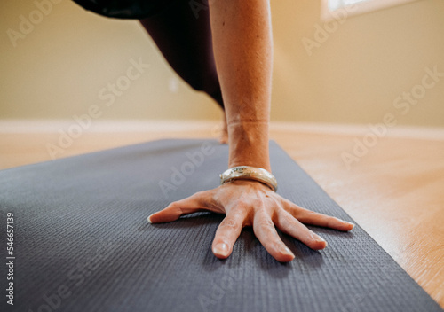 Close up of a female hand with bracelet on a yoga mat in a studio photo