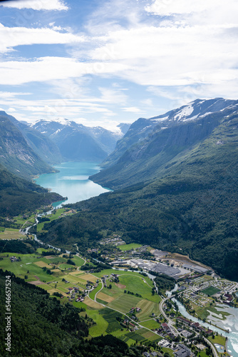 Norwegian mountain landscape from a high mountain down in the valley there is a village and in the distance between the mountain you can see a fjord with blue water above which there is beautiful sky