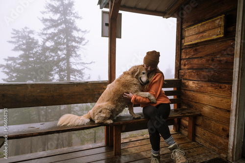 Cute fluffy dog and girl hug on porch of cabin photo