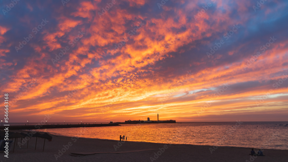 Fototapeta premium Very colorful sunset with the casle of San Sebastian at the horizon in Cadiz, Andalusia, Spain