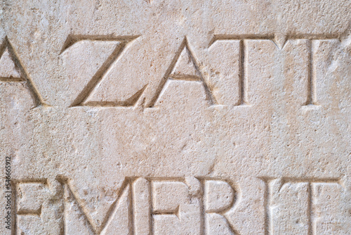 Old carved inscription letters in a light coloured stone surface.