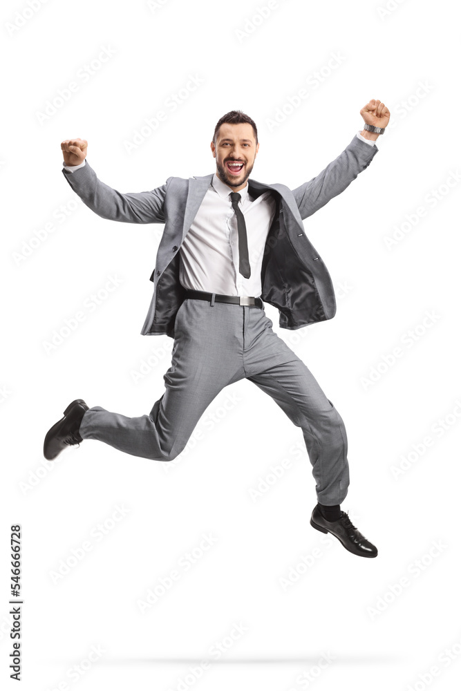 Excited young businessman in a grey suit jumping