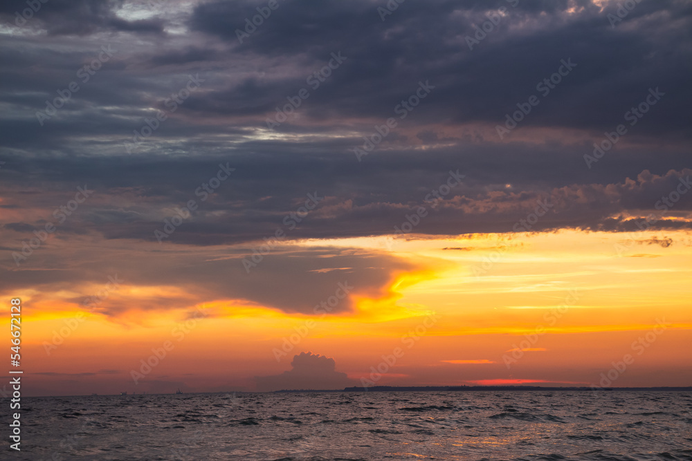 Amazing Black sea sunset. Dark blue сlouds and water landscape . Drama juicy sky. Golden blue hour at the ocean romantic evening. The red sun reflects in the water. Horizon background and surf line.