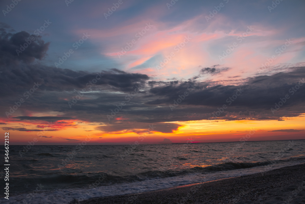 Amazing Black sea sunset. Dark blue сlouds and water landscape . Drama juicy orange sky. Golden blue hour at the ocean romantic evening. The red sun reflects in the water. Horizon background and surf 