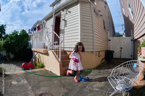 pretty young girl in a summer dress playing in a suburban backyarrd photo