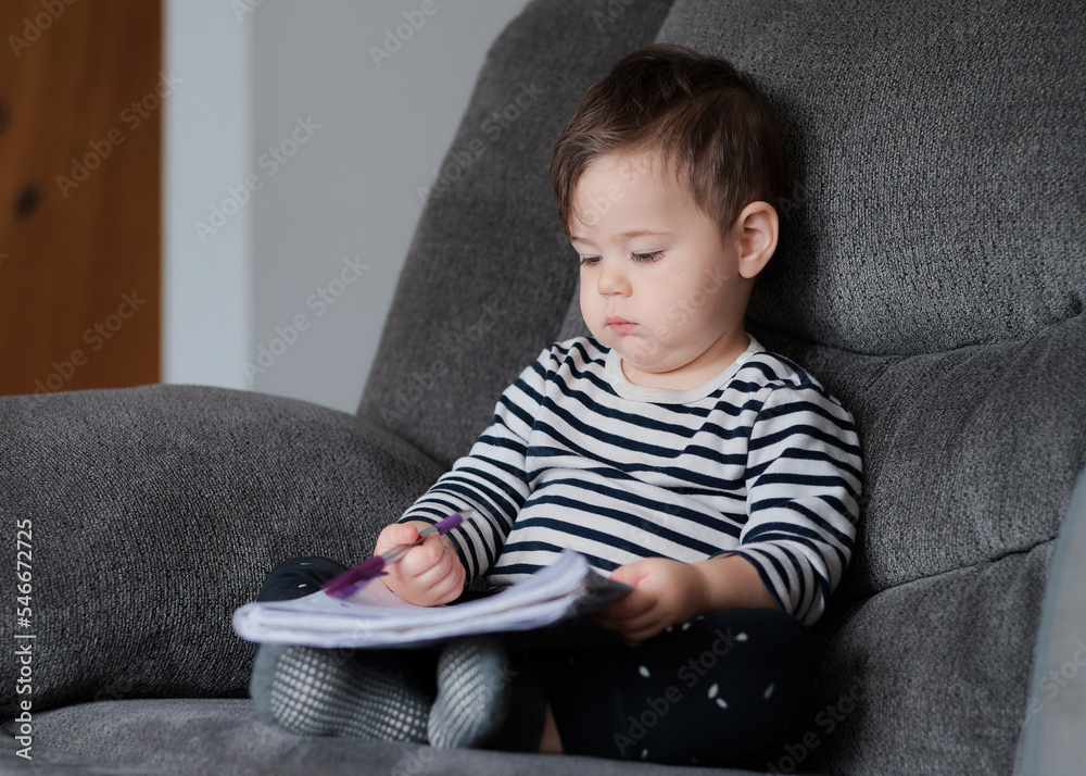 cute baby boy writing in a notebook on the couch at home cute baby boy writing in a notebook on the couch at home