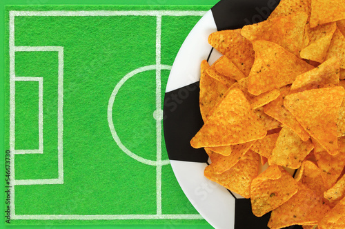 Obraz na płótnie Mexican corn nacho chips on big plate painted like soccer ball, green felt dish mat like football field with place for text. Template of football soccer party table. Top view, copy space, mockup. w salonie