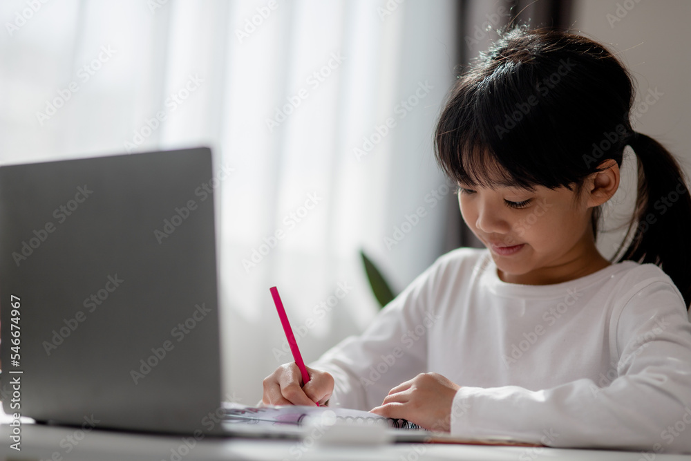 Asian schoolgirl doing her homework with laptop at home. Children use gadgets to study. Education and distance learning for kids. Homeschooling during quarantine. Stay at home Asian schoolgirl doing her homework with laptop at home. Children use gadgets to study. Education and distance learning for kids. Homeschooling during quarantine. Stay at home