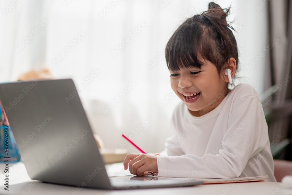 Asian schoolgirl doing her homework with laptop at home. Children use gadgets to study. Education and distance learning for kids. Homeschooling during quarantine. Stay at home Asian schoolgirl doing her homework with laptop at home. Children use gadgets to study. Education and distance learning for kids. Homeschooling during quarantine. Stay at home