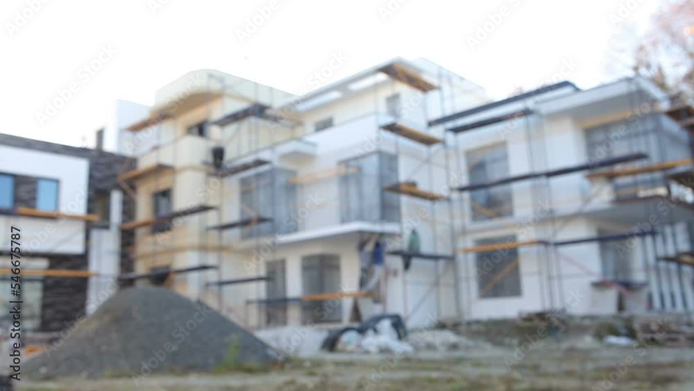 Blurry video. Construction of a new two-story cottage house. Workers on scaffolding make the facade of the house. Construction site. Blurry video. Construction of a new two-story cottage house. Workers on scaffolding make the facade of the house. Construction site.