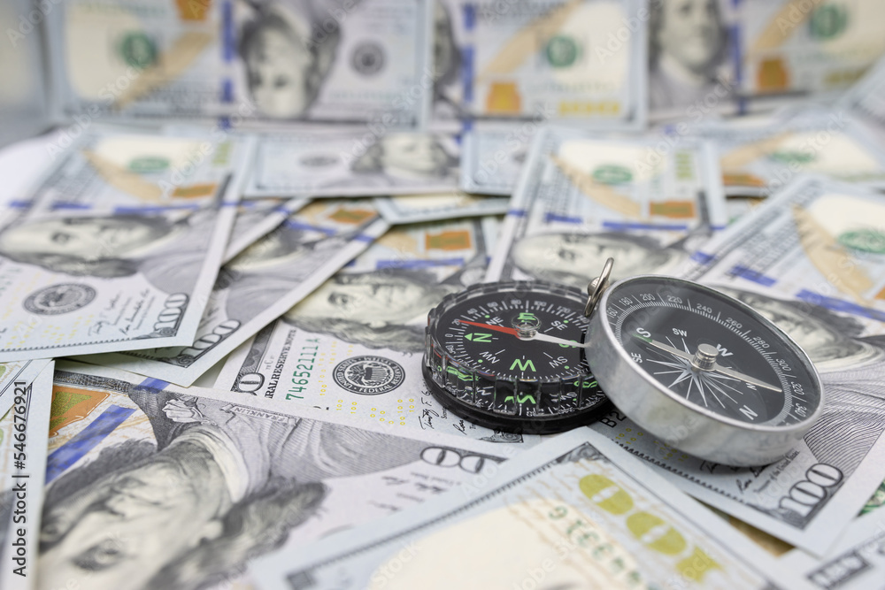 Classic navigational compass on the background of one hundred dollar bills Classic navigational compass on the background of one hundred dollar bills