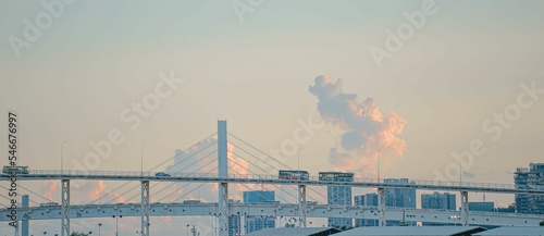 Landscape view of vehicles passing over bridges, with a cityscape in the background, during sunset