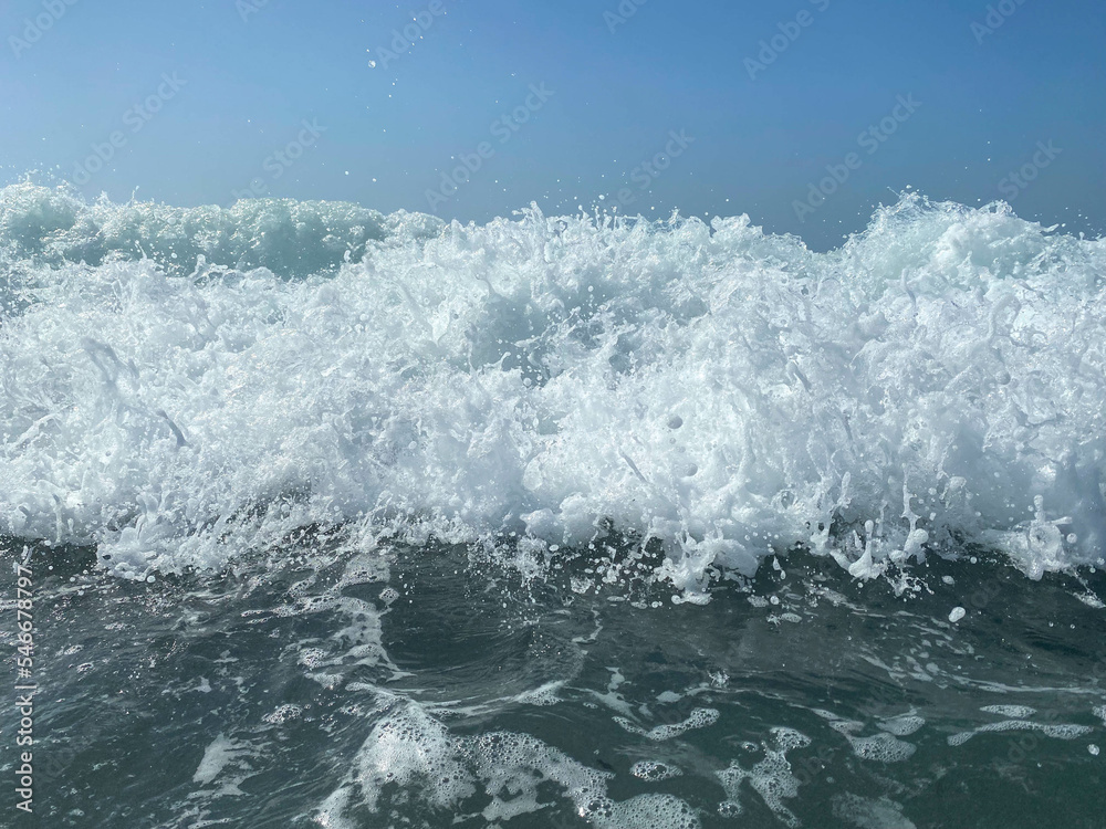 Beautiful sea with waves splashing warm sparkling clear blue water in a warm tropical oriental country southern resort. Background, texture