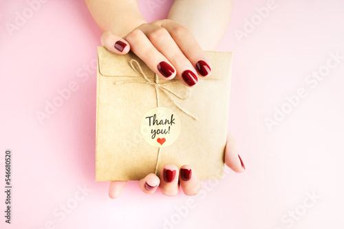 Female hands hold a decorative envelope on a pink background
