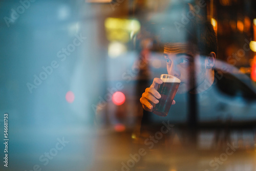 A man drinks soda with foam in a bar