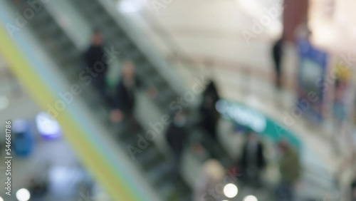 defocused blurred shopping mall escalators ing up and down unrecognizable people walking stairs in shopping center store. modern department store blurred costumers defocused lights bokeh abstract  photo