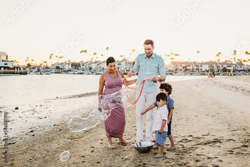 Family blowing giant bubbles on beach