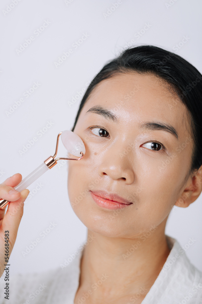 Woman doing self massage with rose quartz face roller Woman doing self massage with rose quartz face roller