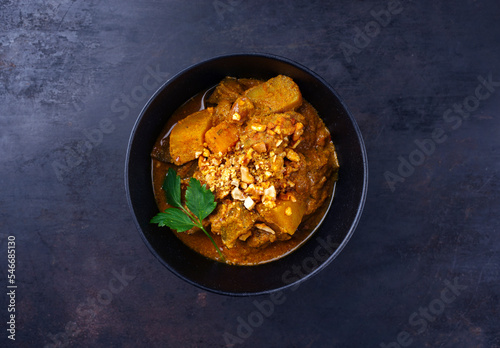 Traditional Indian vegetarian Madras curry stew with sweet potatoes and roasted cashew nuts served as top view in design bowl with copy space