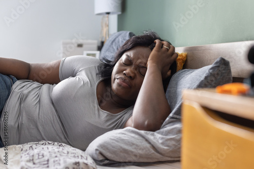 malaise, hangover or headache, sick woman feeling bad in the bedroom photo