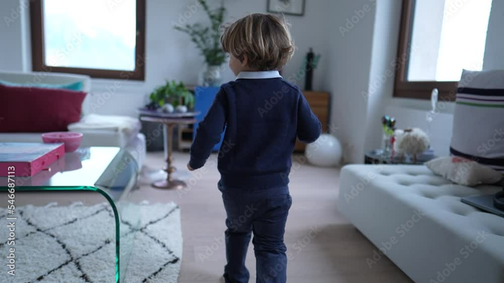 Back of one little boy running at home indoors. Child full of energy runs in modern house apartment. Small kid runner Back of one little boy running at home indoors. Child full of energy runs in modern house apartment. Small kid runner
