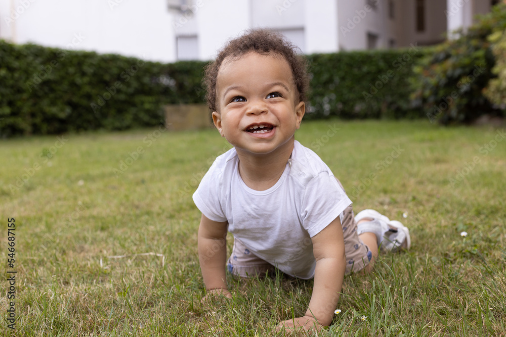 happy smiling baby boy crawling on the grass in city park in summer happy smiling baby boy crawling on the grass in city park in summer