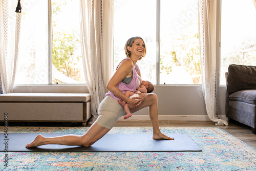 New Mother Does Yoga On A Mat While Nursing Child photo