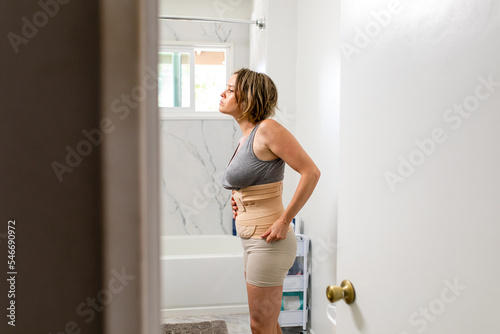 Woman Looks In The Mirror After Putting On A Belly Wrap
