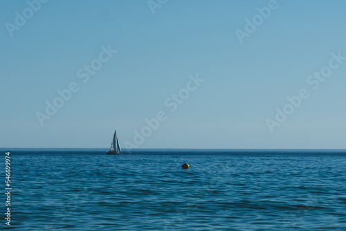 Blue sky and sea with a sailboat © Penteas