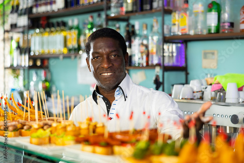 Fotografía View on the adult African man standing at the food display at the bar