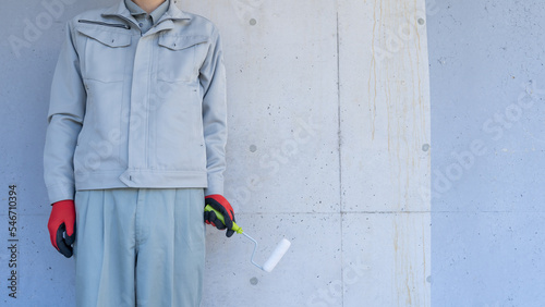 外壁塗装のイメージ｜コンクリート壁とペイントローラーを持つ作業員