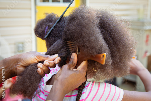 Mother combing her child's kinky curly coily hair photo