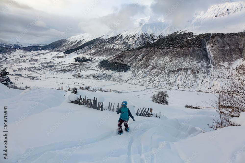 A girl freerides on a snowboard on the background of the peak of Ushba in the resort of Tetnuldi, Mestia, Svaneti, Caucasus