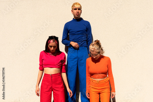 Three friends with same color clothes over wall