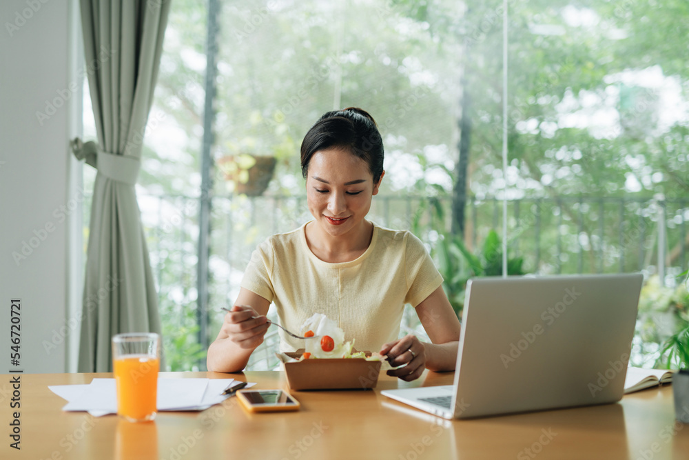 Business woman eating meals from lunch box at working table Business woman eating meals from lunch box at working table