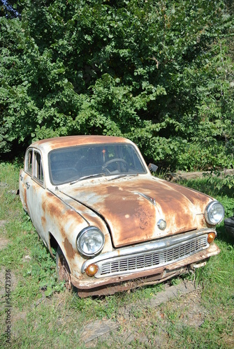 Old soviet rusty car in the forest on a sunny day 