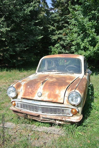 Old soviet rusty car in the forest on a sunny day 