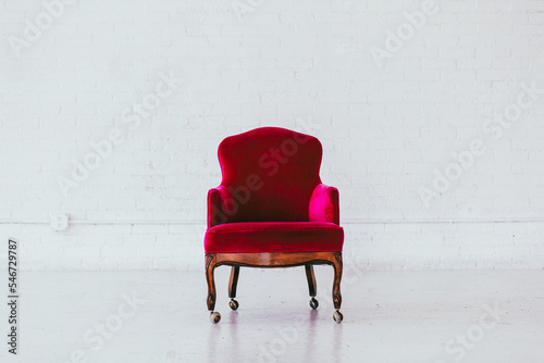 Vintage red velvet wingback chair in a white brick studio photo
