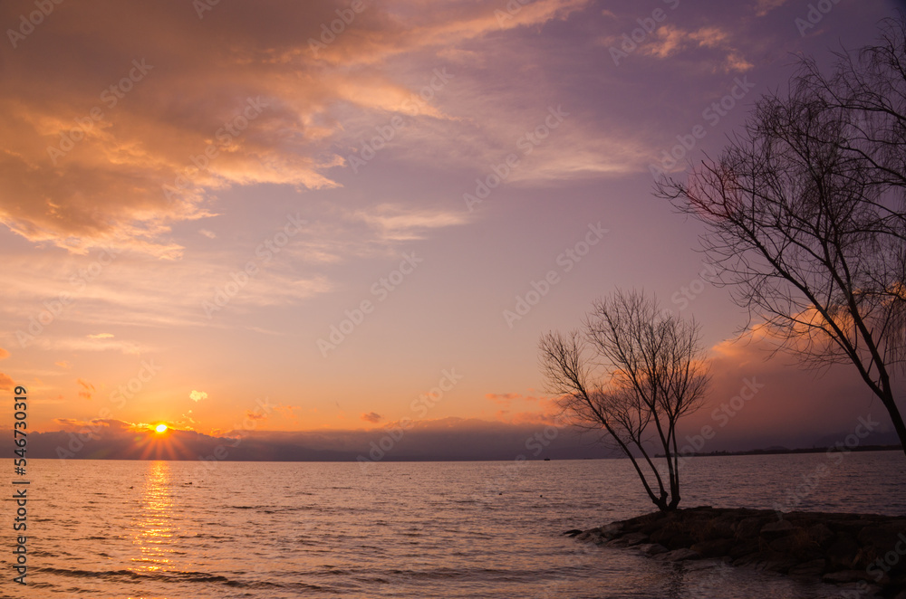 水平線に沈む夕陽とオレンジ色に染まった雲の風景 水平線に沈む夕陽とオレンジ色に染まった雲の風景