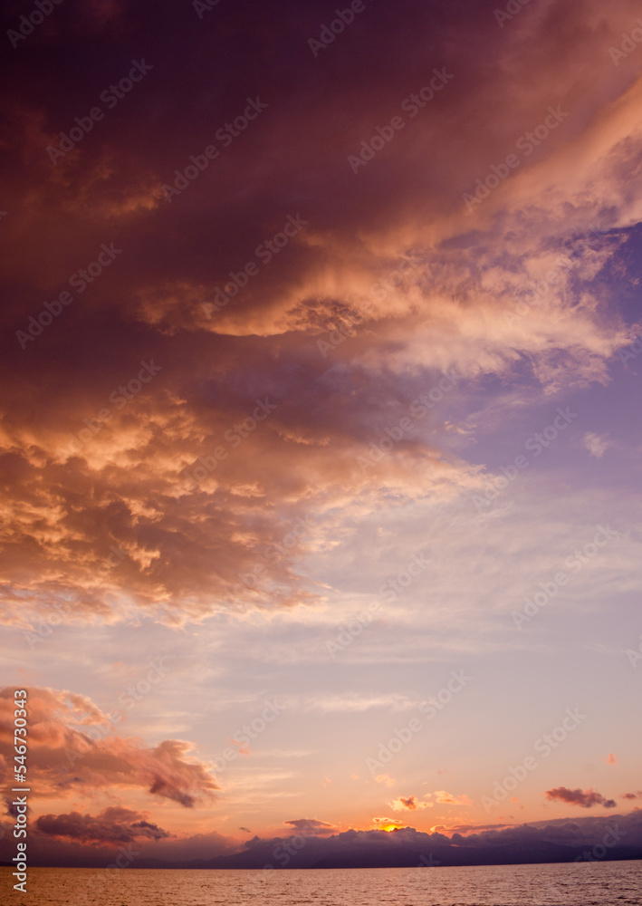 水平線に沈む夕陽とオレンジ色に染まった雲の風景 水平線に沈む夕陽とオレンジ色に染まった雲の風景