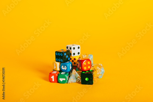 Various colorful dice pieces on a vibrant yellow background photo