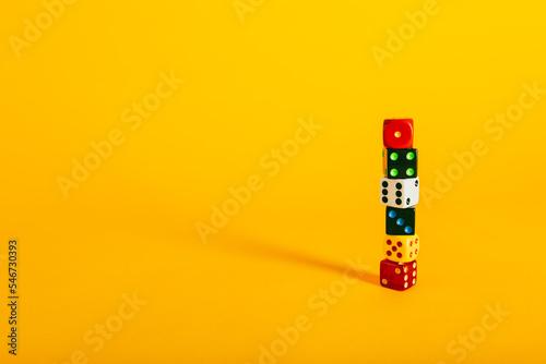 Colorful dice pieces and dice stacked on a vibrant yellow background