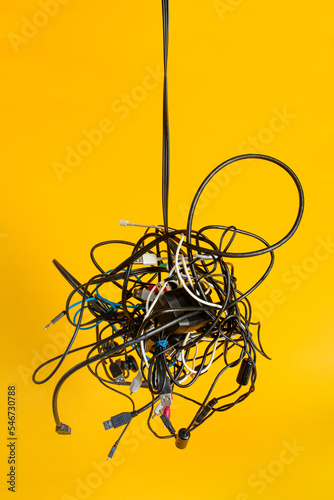 A hanging messy bundle of tangled electronic cords and wires