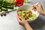 Woman making tasty salad with Chinese cabbage at light grey table, closeup